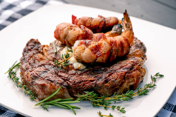 Char-Grilled Ribeye Steak with Thyme and Rosemary with Bacon-Wrapped Jumbo Shrimp or Prawns on a Plate, Ready to Eat - Keto Friendly