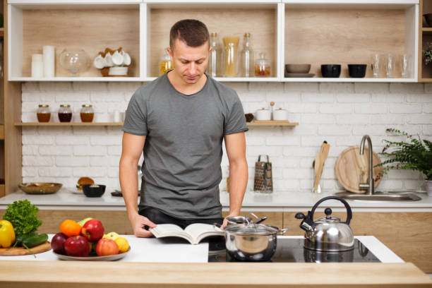 paleo, keto, detox diet food, slimming and weight loss. fit muscled man reading recipe book before cooking