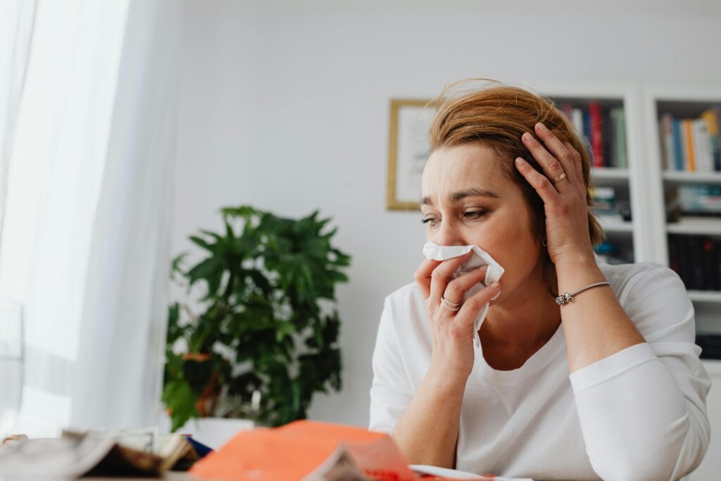 A woman with a tissue over her mouth because she doesn't feel well. She has the Keto Flu.